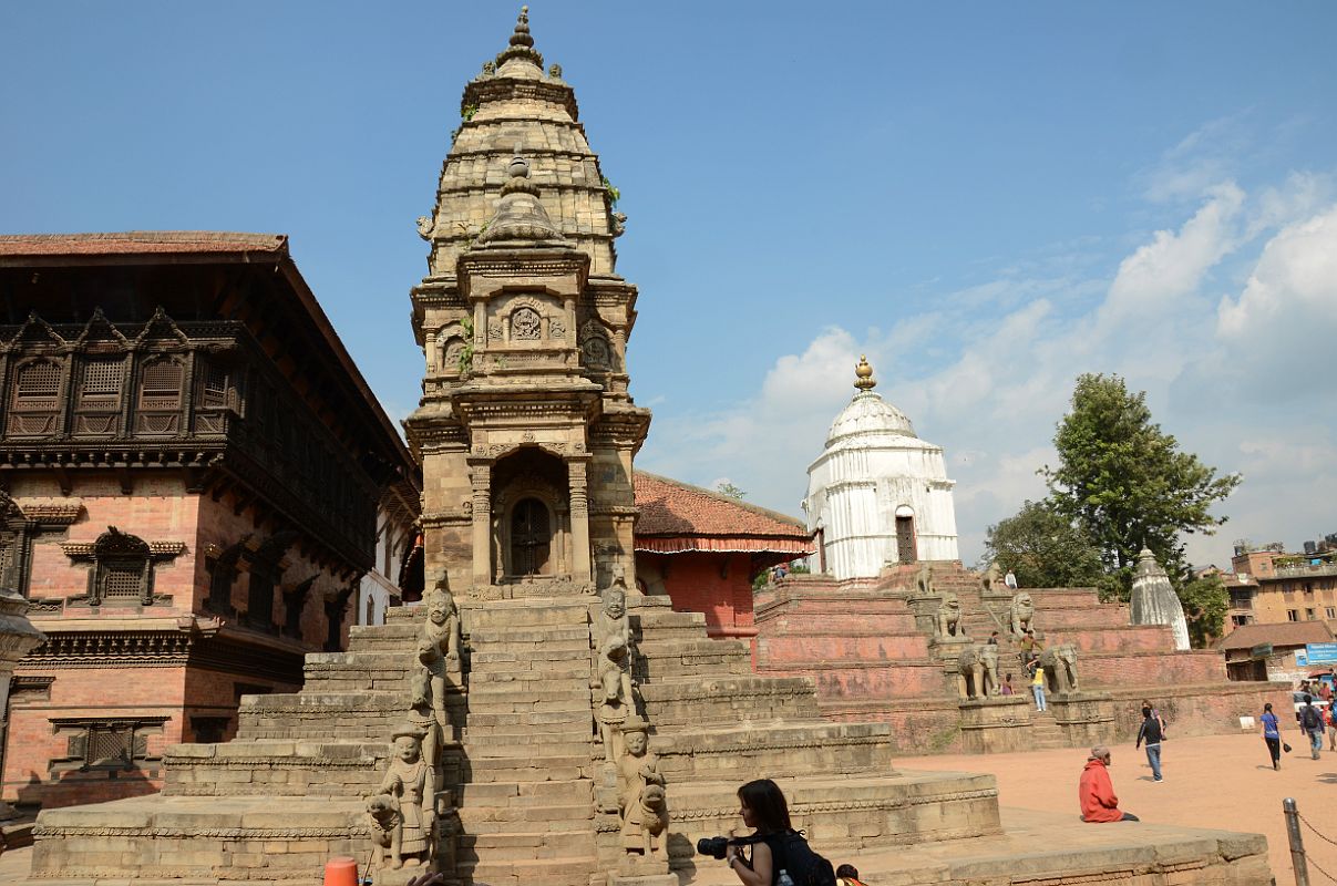 Kathmandu Bhaktapur 03-3 Bhaktapur Durbar Square Stone Siddhi Lakshmi Temple And White Fasidega Temple The steps to the stone Siddhi Lakshmi Temple, also known as Lohan Dega, are flanked by male and female attendants with a child and dog, horses, rhinos, man-lions and camels. The large white Fasidega Temple on the right sits on a six-level plinth and is dedicated to Shiva.